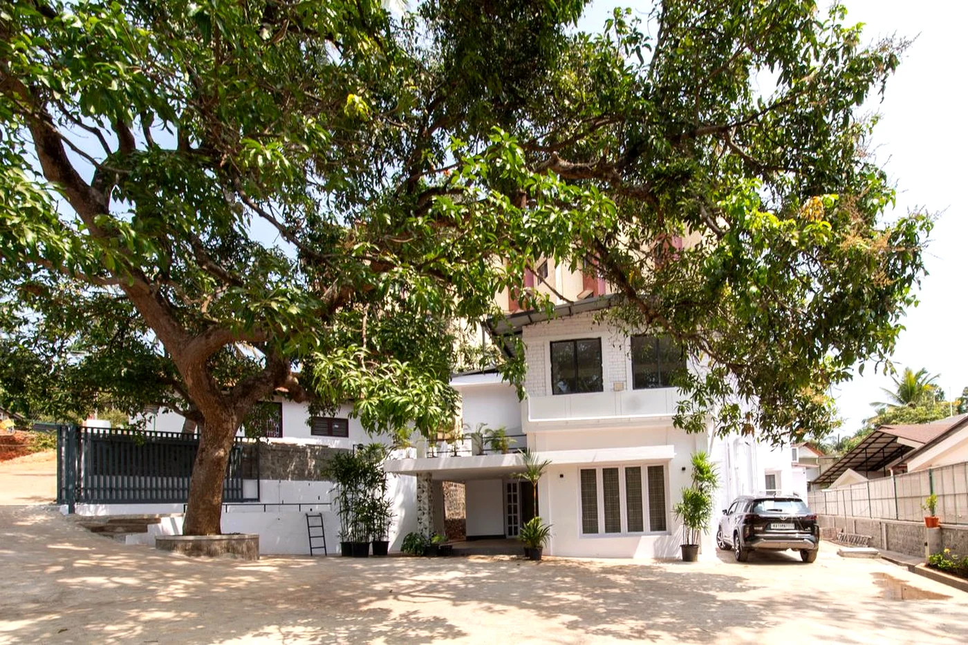 Front exterior of Mango Tree Homestay in Mangalore with driveway and shade tree.